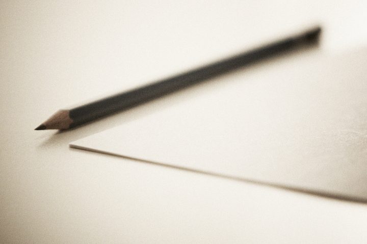 Een potlood naast de hoek van een onbeschreven vel papier